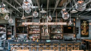 Wide shot of a bar with stools and hanging overhead lights in an industrial setting